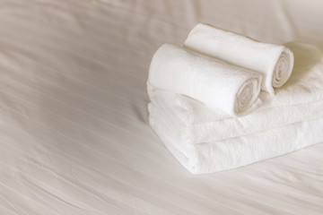 white fluffy towels on bed in hotel bedroom. Close up view