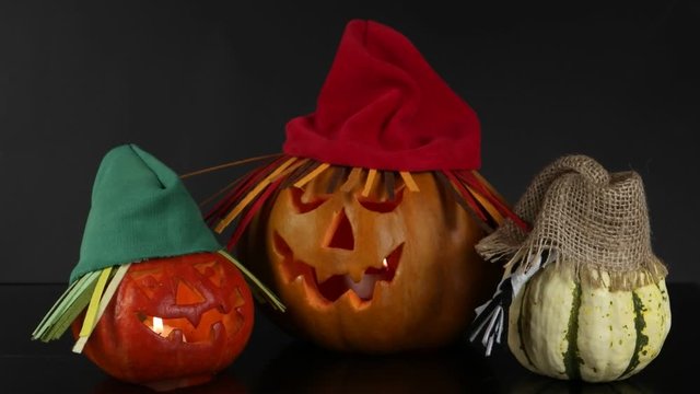 Three funny halloween pumpkins in hats are placed on a black background