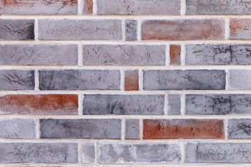 Close up old rough textured wall of red and gray bricks with stains and cracks with a white seam. Abstract grunge background
