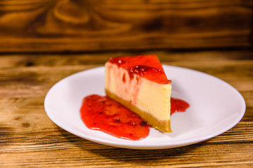 White plate with cheesecake New York and raspberry jam on wooden table