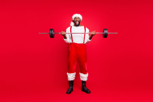 Full length photo of excited santa claus in xmas headwear hat holding sportive equipment screaming wow omg wearing white jumper pants trousers isolated over red background