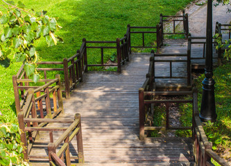 wooden staircase made of wooden handrails of unusual shape on the background of green grass