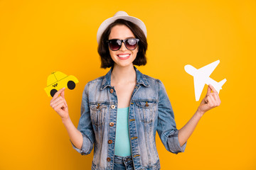 Photo of charming nice cute attractive funky funny positive girl wearing cap jeans denim comparing different kinds of transport while isolated with yellow background