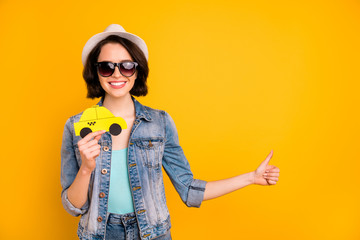 Photo of charming toothy beautiful interesting girl wearing cap jeans denim jacket adverting you some taxi while isolated with yellow background - obrazy, fototapety, plakaty
