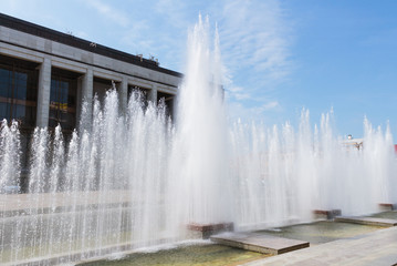 high multi-level fountain on the background of a dark building and blue sky with Cirrus clouds