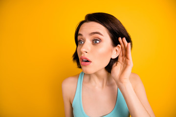 Photo of stunned shocked eavesdropping girlfriend trying to hear someone conversation attentively while isolated with yellow background