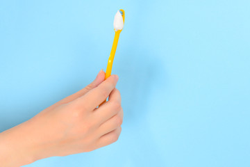 Woman holds toothbrush with toothpaste in her hand on a blue background.