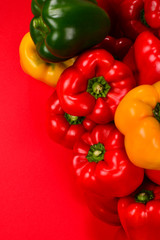 Fresh red, yelow, green bell pepper on a red background.