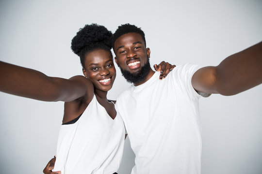 Couple selfie. Studio shot of casual african-american couple grimacing on white studio background, copy space, isolated