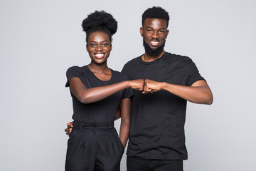 Beautiful young African woman bumping hands her boyfriend and looking at camera while standing...