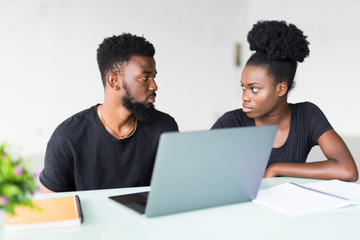 Two young african coworkers working together in a modern office. African black business partners using laptop and discussing new startup project.