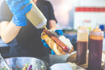 Man holding hot dog and adding mustard. Street fast food vendor concept.