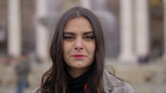 Attractive young latin woman smiling at camera in the city