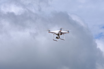 White drone quadcopter flying on the air for take a photo and video with white cloudy background.