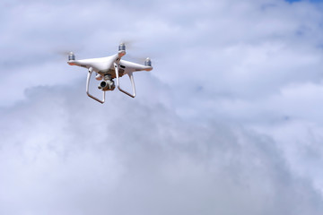 White drone quadcopter flying on the air for take a photo and video with white cloudy background.