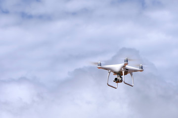 White drone quadcopter flying on the air for take a photo and video with white cloudy background.