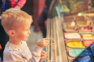 teen boy chooses pastries in a cafe. a child next to a showcase with goods