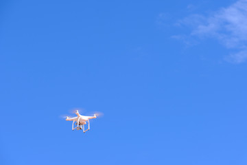 White drone quadcopter flying on the air for take a photo and video with blue sky background.