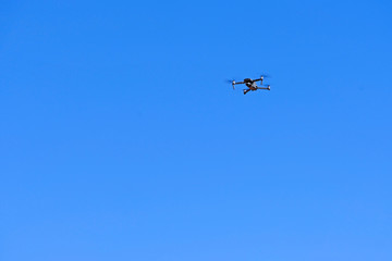 Black drone quadcopter flying on the air for take a photo and video with blue sky background.