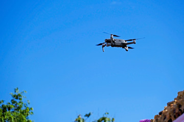 Black drone quadcopter flying on the air for take a photo and video with blue sky background.
