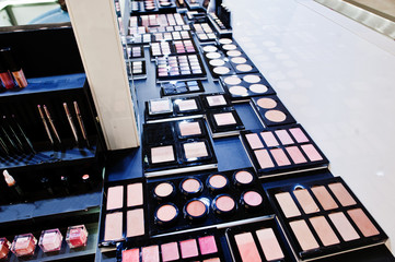 Multicolor lipstick or eye shadow makeup pallette on shelf in the shop.