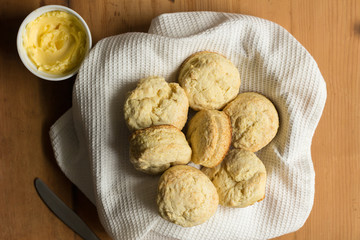 Scones - Biscuits made with buttermilk recipe in bowl with white dish towel, butter and knife on wooden table