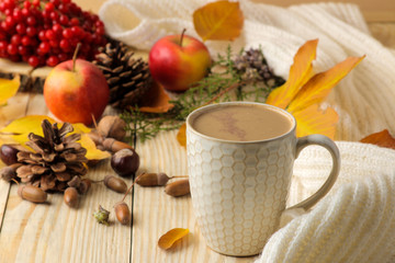 Hot autumn drink, coffee or cocoa, with yellow leaves and decorative pumpkins, acorns and apples on a natural wooden table. autumn composition.