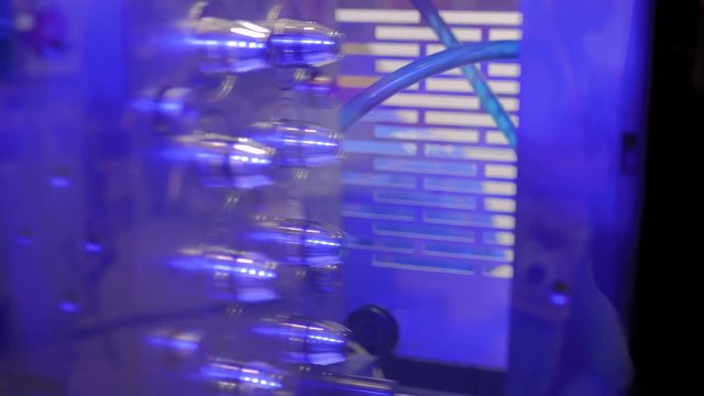 Automatic plastic injection molding machine working in demonstration mode with blue illumination light at exhibition, trade show. Manufacturing, industrial, recycling, automated technology concept