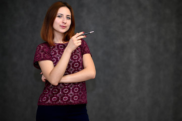 Fototapeta premium Portrait of a brunette girl with beautiful brown hair in a purple t-shirt on a gray background. He stands in different poses, demonstrates emotions.
