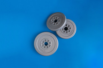 three gray plastic dumbbell pancakes on the color surface