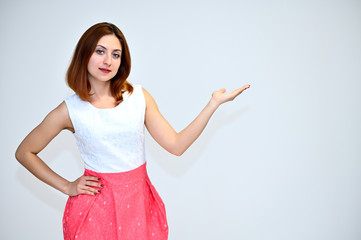 Portrait of a brunette girl with beautiful brown hair in a pink and white dress on a white background. He stands in different poses, demonstrates emotions.