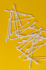 bunch of cotton ear sticks swabs on yellow surface, macro view