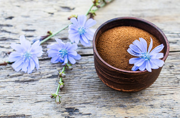 Obraz na płótnie Canvas Blue chicory flower and a bowl of instant chicory powder on an old wooden table. Chicory powder. The concept of healthy eating a drink.
