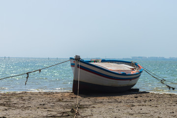 Fototapeta premium Blue, white and red boat on the seashore