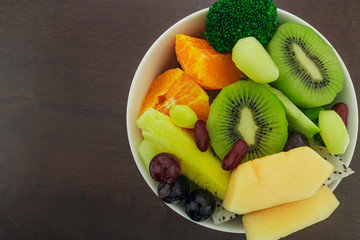 Bowl of healthy fresh fruit salad on wooden background. Concept for healthy food.