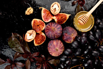 Autumn frame background. Autumn food still life with season fruits grape and figs, honey on a black table. Thanksgiving day.