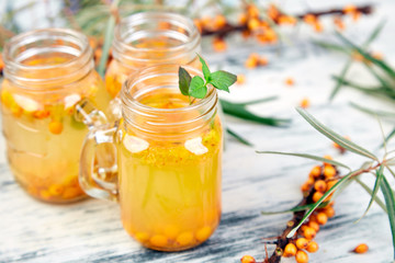 Hot sea buckthorn tea with ginger and honey and sea buckthorn berries on white table. Top view. Vitaminic healthy.