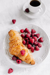  Croissant with raspberries on a plate and a cup of coffee