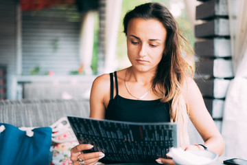 Attractive young woman in outdoor cafe with menu