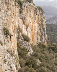 A man is walking along a stretched sling. Highline in the mountains. Man catches balance....