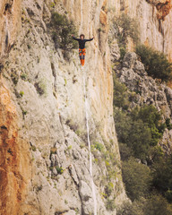 A man is walking along a stretched sling. Highline in the mountains. Man catches balance....