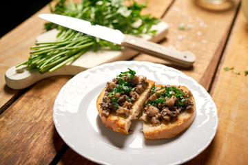 Toasts with mushrooms on white plate on wooden kitchen table