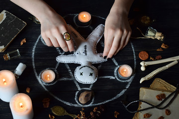 In Voodoo doll are needles pricked. Candles, pentagram, stones, love potion and old books on witch...