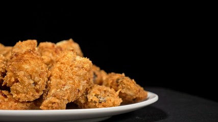 Cool beautiful fresh juicy cooked chicken wings in breading. Buffalo wings spread on food in white plate. Cooking with deep fryer fry machine.