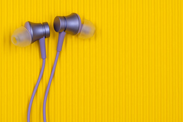 Purple audio earphones on the yellow background