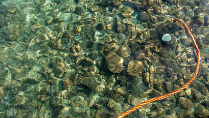 Obraz na płótnie Canvas red colored rope in crystal clear sea water closeup
