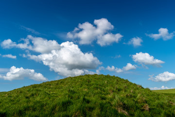 Fototapeta na wymiar Grassy Hill with Clouds