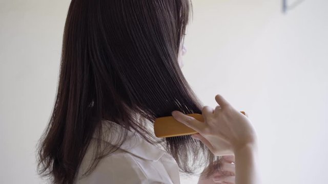Back view of woman unraveling her hair with a brush
