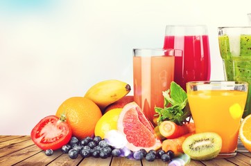 Fototapeta na wymiar Composition of fruits and glasses of juice on blurred natural background