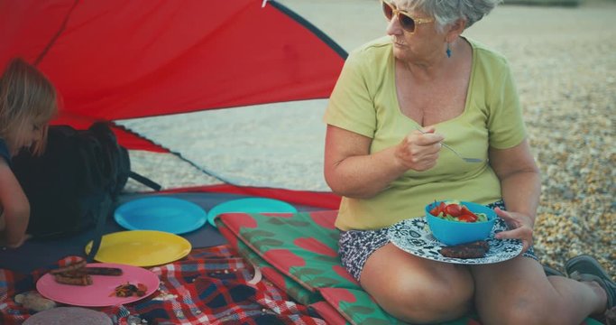 Toddler and grandmother enjoyoing barbecue on the beach